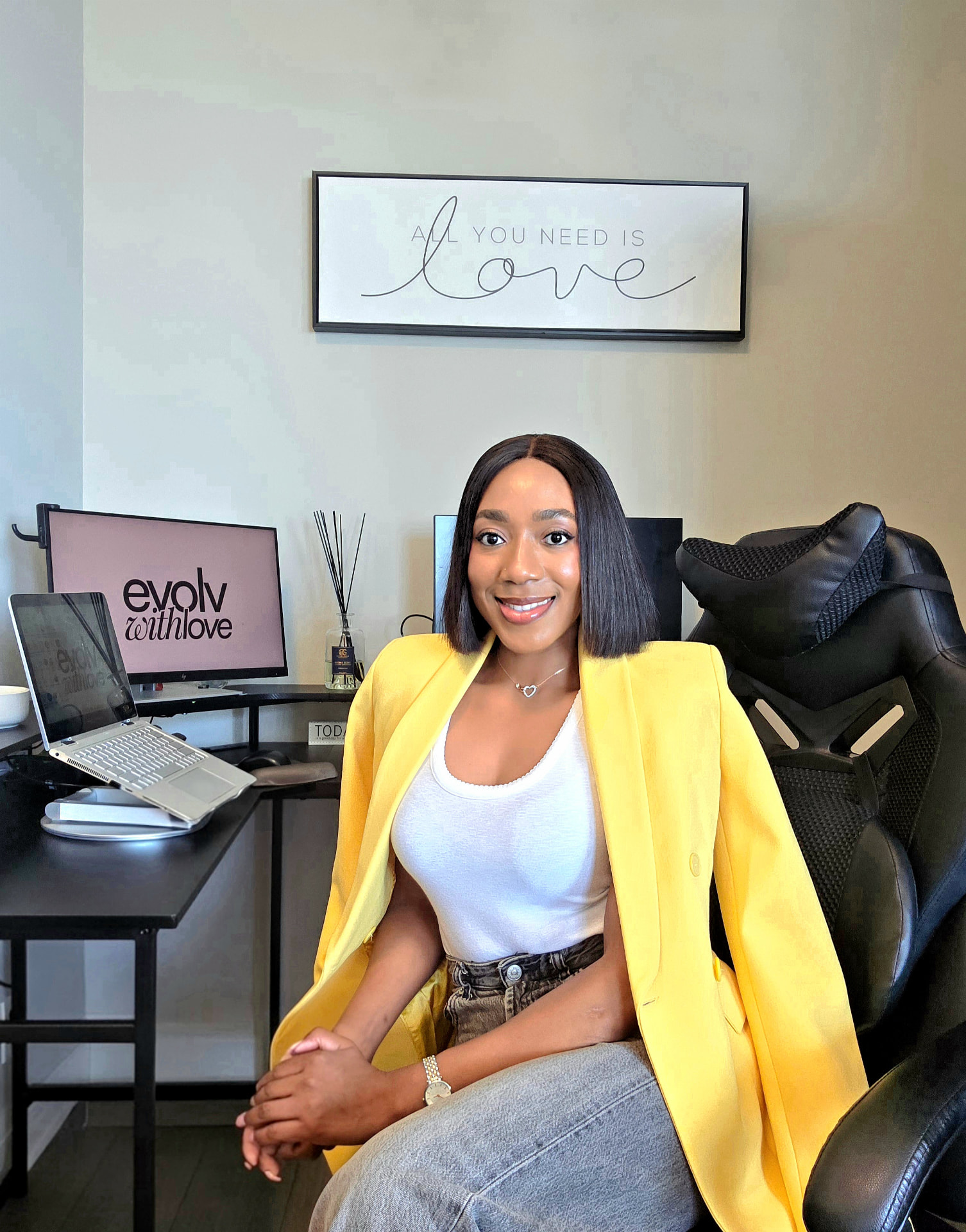 Love seated in her office beneath an All You Need Is Love sign